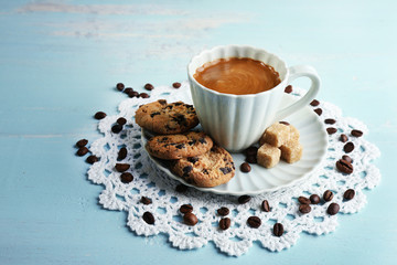 Cup of coffee and tasty cookie on color wooden background