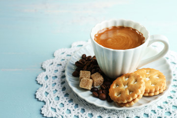Cup of coffee and tasty cookie on color wooden background