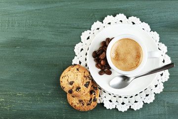 Cup of coffee and tasty cookie on color wooden background