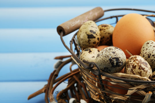 Bird eggs in wicker basket on color wooden background