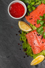 Fresh salmon and red caviar on black plate