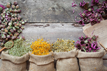 Healing herbs in hessian bags on old wooden rustic table, herbal - obrazy, fototapety, plakaty