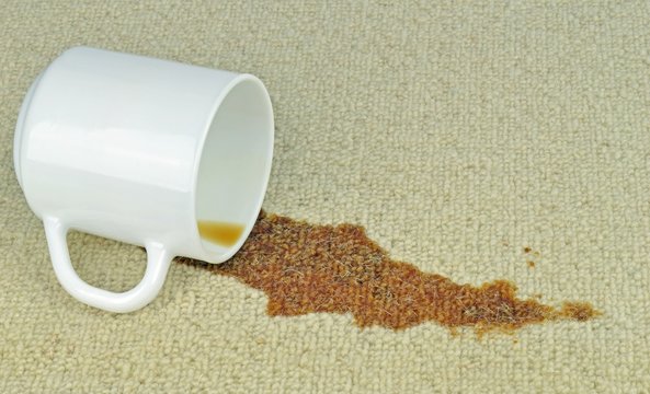 A spilled cup of coffee on a carpet with stain