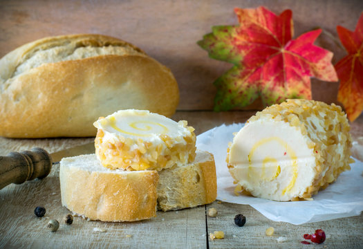 A Roll Of Soft Cheese And Bread On Rustic Board