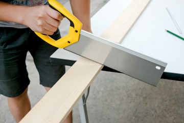 Carpenter working on a hand saw cutting wood board