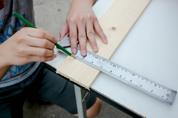 Carpenter working on a hand measuring wood board with ruler