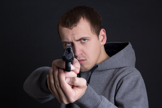 man criminal aiming with gun over grey