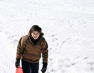Fototapeta na wymiar young boy walks with tobogganing on fresh snow in the winter