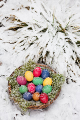 Colored eggs in a basket in snow