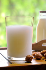 Glass of almond milk on a table with almonds front view closeup