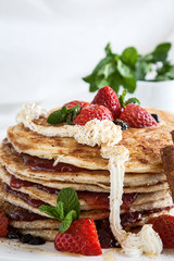 White plate full of pancakes with raspberries strawberries blueb