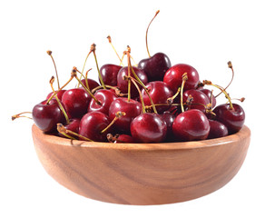 Red cherries in a wooden bowl on a white