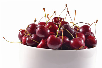 Red cherries in a white bowl on a white