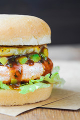Homemade fish burger with salmon, avocado and pineapple.Close up