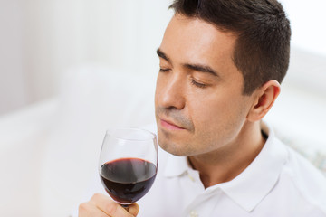 happy man drinking red wine from glass at home