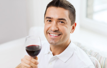 happy man drinking red wine from glass at home