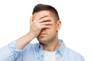 unhappy man covering his eyes by hand