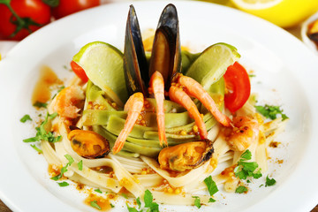 Tasty pasta with shrimps, mussels, tomatoes on plate close-up