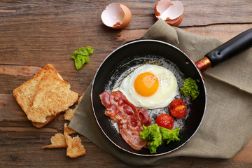 Bacon and eggs on rustic wooden planks background