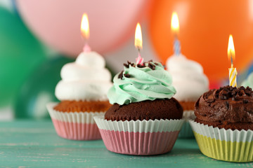 Delicious birthday cupcakes on table on bright background