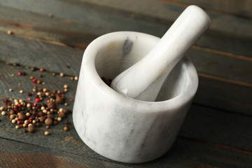 Mixture of peppers in mortar on wooden background