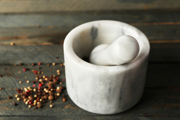 Mixture of peppers in mortar on wooden background