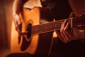 woman's hands playing acoustic guitar, close up