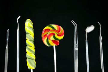 Dentist tools with lollipops on dark background