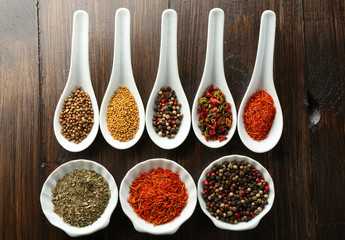 Different kinds of spices in bowls and spoons, close-up,