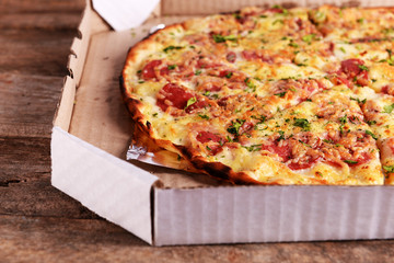 Tasty pizza in box on wooden background