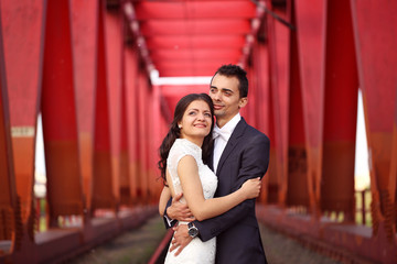 Bride and groom celebrating on a red bridge
