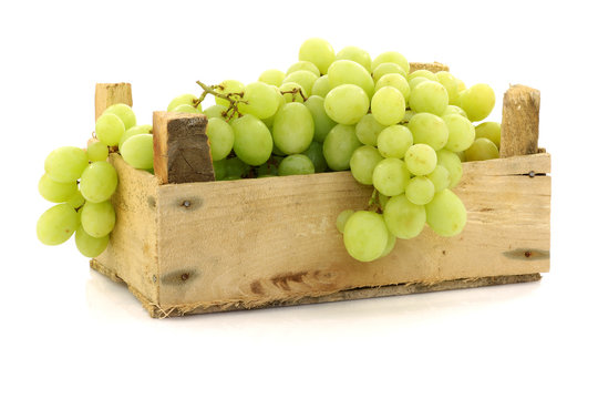 fresh white grapes in a wooden box on a white background