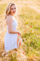 Fototapeta na wymiar Lonely beautiful young blonde girl in white dress with straw hat