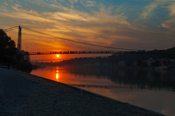 Fototapeta premium View of River Ganga and Ram Jhula bridge at sunset