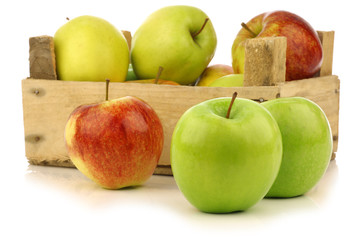assorted fresh apples in a wooden crate on a white background