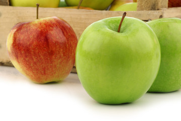 assorted fresh apples in a wooden crate on a white background