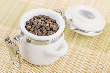 Peppercorns - Black peppercorns in a white jar.
