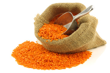 red lentils in a burlap bag on a white background