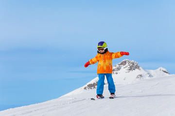 Boy with ski mask and arms apart skiing in winter