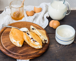 thin pancakes with cottage cheese, prunes, honey and sour cream