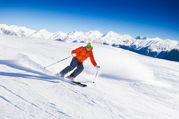 Fototapeta na wymiar Skier in mask slides fast while skiing from slope