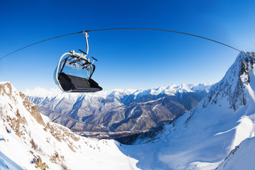 Chair on ski lift over mountain peaks panorama