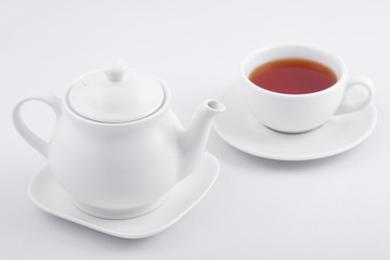 Obraz na płótnie Canvas white tea cup with tea and white teapot on white background