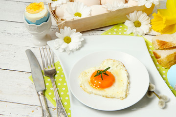 Easter table setting with flowers and eggs on old wooden table