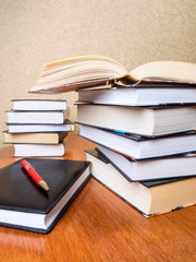 Pile of books, notepad and pen on the table