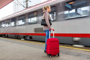 Frau wartet auf Zug auf Bahnhof - obrazy, fototapety, plakaty