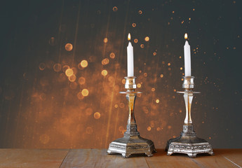 two candlesticks with burning candles over wooden table and vint © tomertu