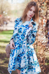 Red-haired girl with a bag posing on meadow