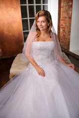 Fototapeta premium beautiful bride sitting posing in her wedding dress. Studio.