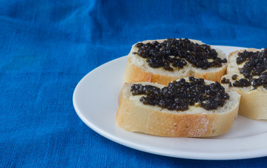 Sandwiches with black caviar lying on white plate